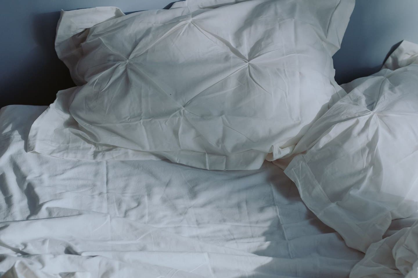 Ungemachtes Bett mit weißer Bettwäsche